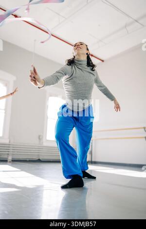 Rhythmic gymnast performing ribbon routine in studio Stock Photo