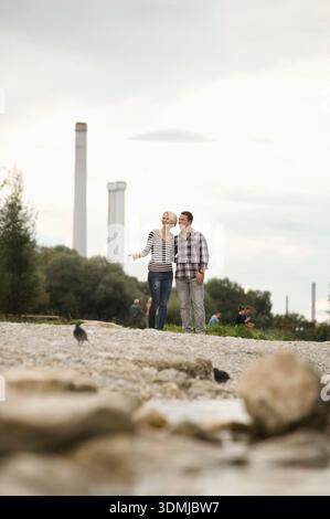 Happy couple hugging and standing by riverside in city Stock Photo