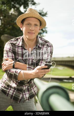 Young relaxed man with hat using smartphone and white headphones Stock Photo