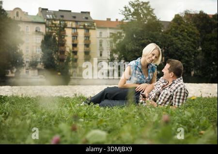 Young couple relaxing together in city on grass near a river Stock Photo