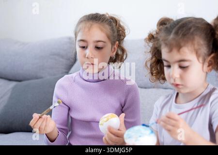 Two sisters decorating Easter eggs.at home Stock Photo