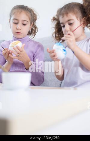 Two sisters decorating Easter eggs.at home Stock Photo
