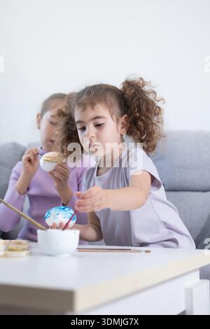 Two sisters decorating Easter eggs.at home Stock Photo