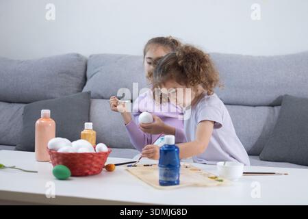 Two sisters decorating Easter eggs.at home Stock Photo