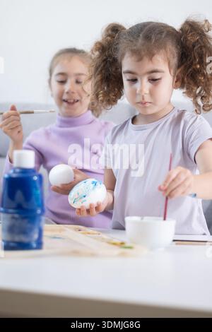 Two sisters decorating Easter eggs.at home Stock Photo