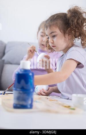 Two sisters decorating Easter eggs.at home Stock Photo