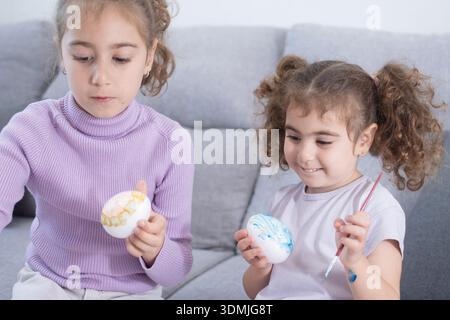 Two sisters decorating Easter eggs.at home Stock Photo