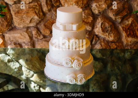 Stunning 4-tier white prop cake for weddings, decorated with elegant ribbons and sugar or biscuit flowers, perfect for event decor inspiration Stock Photo