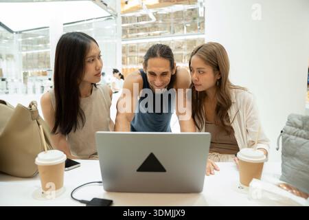 Diverse friends collaborating on creative startup project using laptop Stock Photo