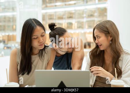 Diverse friends collaborating using laptop in cafe Stock Photo