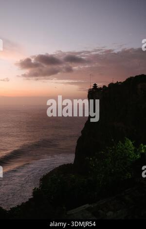 A serene golden sunset glows over the calm sea as white buildings and a ...