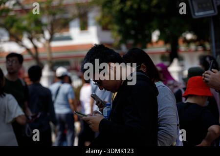 BANGKOK, THAILAND-JAN 16, 2026: Tourists reviewing photo in smartphone and exploring at Wat Thair, side profile, at Wat Arun. Stock Photo