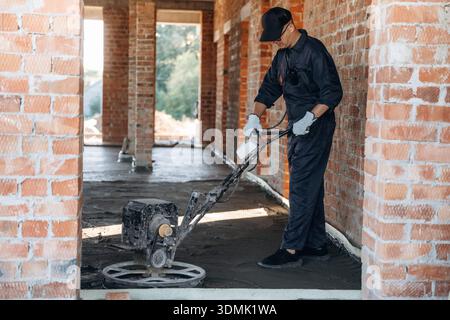 Process of leveling the concrete on the floor. Builder is working on construction site, unfinished building. Stock Photo