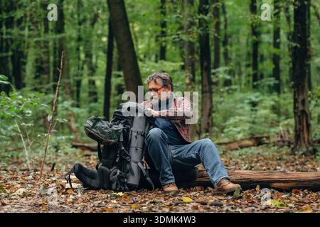 Hiking experience, senior man is in the forest at daytime. Stock Photo