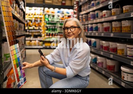 Woman selecting paint colors while sitting in a hardware store during the daytime Stock Photo