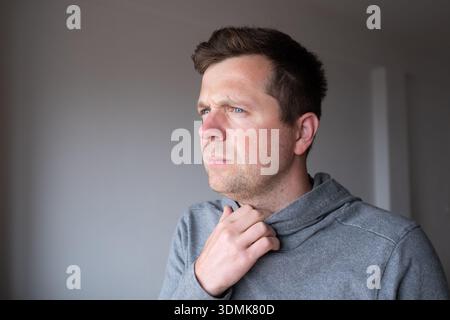 Pensive young man standing at home thinking about problems and making decisions Stock Photo