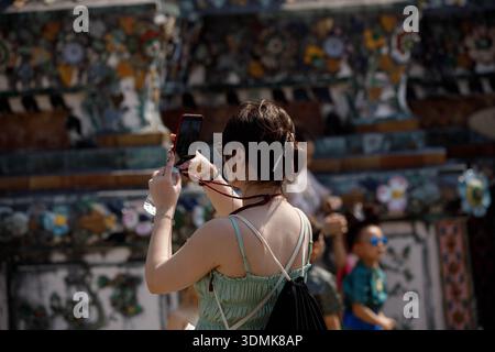 Female backpacker taking a photograph with smartphone and exploring at Thai temple, rear view, Wat Arun. Stock Photo