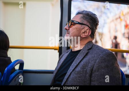 Man in sunglasses and blazer commuting on a bus Stock Photo