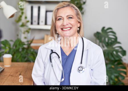Smiling Female Doctor In White Coat With Stethoscope In Modern Clinic Professional Healthcare Office Setting Stock Photo