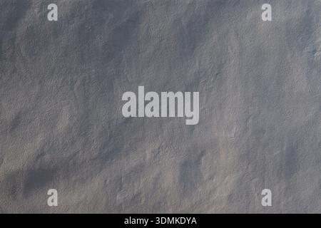Close-up of a clean and uneven painted stone wall in black&white. Beautiful sidelight creates soft shadows. Abstract textured background, copy space. Stock Photo