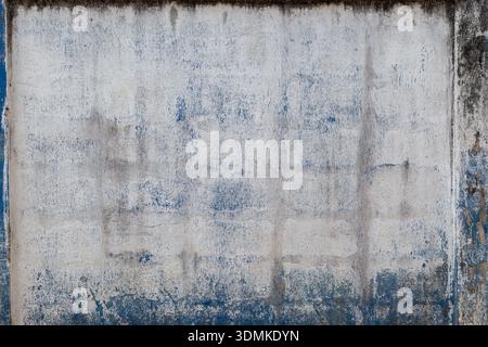 Front view of an old, dirty and plastered white wall with blue paint. High resolution full frame textured grungy background. Stock Photo