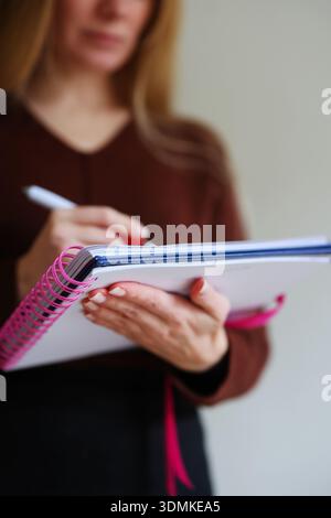 Woman writing notes in spiral notebook. Close up of hands with pen, planning and productivity concept. Stock Photo