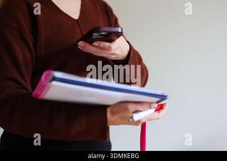 Woman holding notebook and smartphone while taking notes. Productivity, planning and modern work lifestyle concept with copy space. Stock Photo