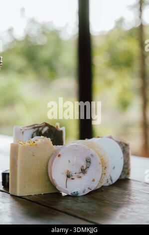 bright soap arrangement, product display showcasing various soaps with lush plant scenery behind Stock Photo