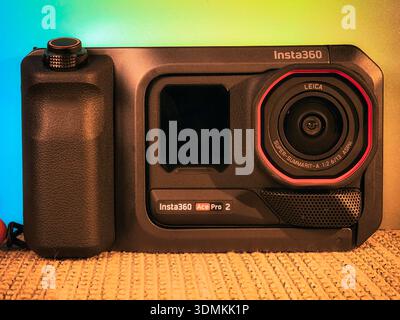 Insta360 Ace Pro 2 action camera featuring Leica lens and red trim photographed in warm studio lighting with gradient background colors. Stock Photo