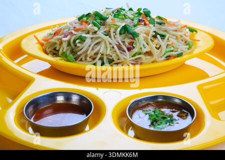 Vegetable noodles served on yellow plate with sauces isolated on white background Stock Photo