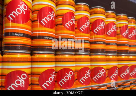 Poznan, Poland - November 22, 2025: Multiple orange and red Mojo Chinotto aluminum cans are neatly arranged, showcasing soft drinks in a supermarket e Stock Photo