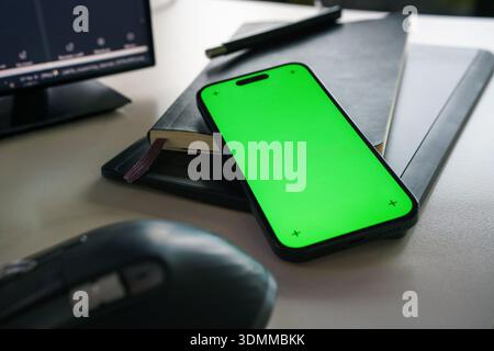 Smartphone green screen mockup desk workspace. Mobile device resting notebook office desk environment business technology application presentation int Stock Photo