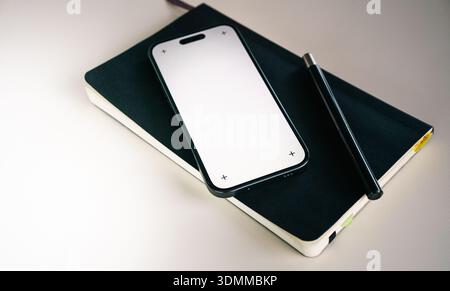 Smartphone notepad blank screen mockup workspace. Mobile device placed notebook minimal desk setup clean professional environment productivity plannin Stock Photo