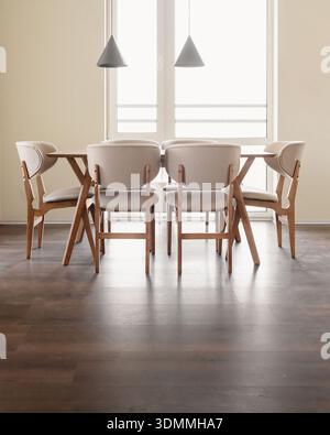 Modern dining room set against a bright, large window. Stock Photo