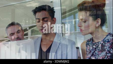 Analyzing three professionals leaning over laptop in office, gray blazer man pointing at charts Stock Photo