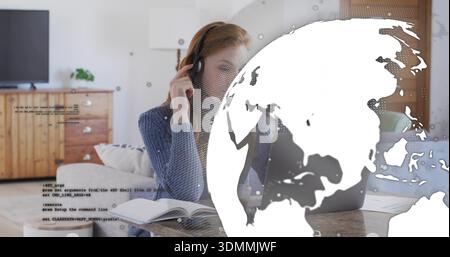Working woman wearing blue knit sweater and headset typing on laptop at home table, globe overlay Stock Photo