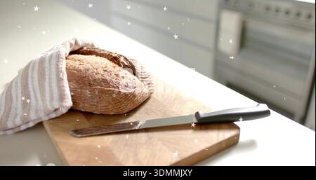 Sitting rustic loaf on board at kitchen counter, with striped towel and serrated knife, copy space Stock Photo
