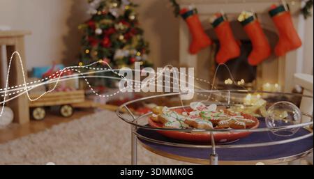 Showing red plate of iced gingerbread cookies resting on metal table at home, glass bauble glinting Stock Photo