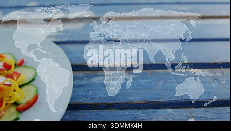 Displaying faint world map centered on worn blue slats, with plate holding cucumber, pepper, tomato Stock Photo