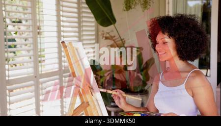 Painting woman in white tank holding brush palette at sunny studio with easel canvas, copy space Stock Photo
