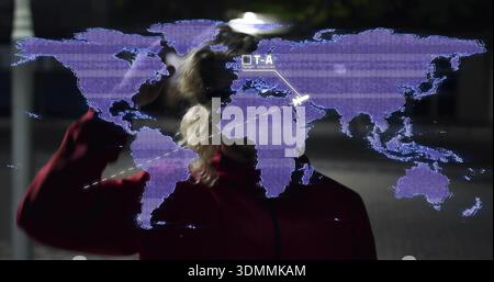 Standing man wearing red zip-up jacket raising hand at night plaza, displaying purple hologram map Stock Photo