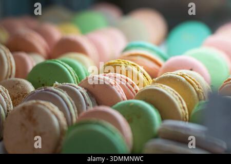 Close up of assorted pastel macarons in patisserie case, layered cookie rounds with crisp shells and creamy filling edge, soft blur background for gou Stock Photo
