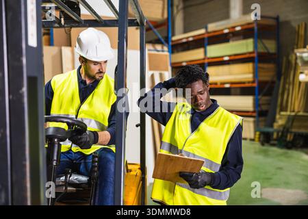 Warehouse workers collaborating on logistics in lumberyard Stock Photo