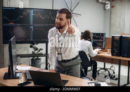 You are doing great, pointing the finger with hand gesture. Two male exchange workers are in the office together. Stock Photo