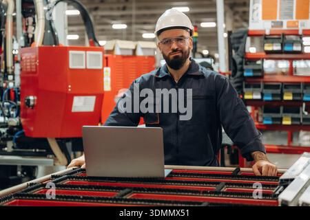 Silver colored laptop, using it. Warehouse worker in an industrial environment of a factory or storage area. Stock Photo