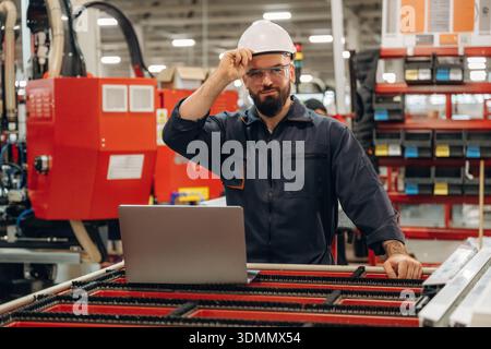 Silver colored laptop, using it. Warehouse worker in an industrial environment of a factory or storage area. Stock Photo