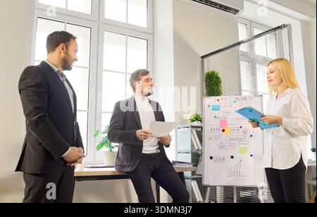 Team leaders listening to presenter by flipchart during office coaching session Stock Photo