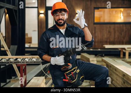White gloves are on hands. Portrait of a male carpenter posing in a woodworking workshop. Stock Photo
