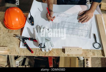 Close-up of hands working with blueprints and tools on a construction table. Stock Photo
