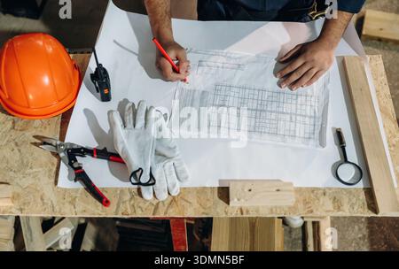 Close-up of hands working with blueprints and tools on a construction table. Stock Photo